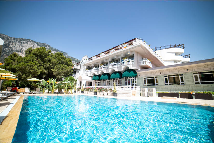 Venkovní bazén s lehátky a palmami, obklopený budovou hotelu. - Venkovní bazén s lehátky a palmami, obklopený budovou hotelu.