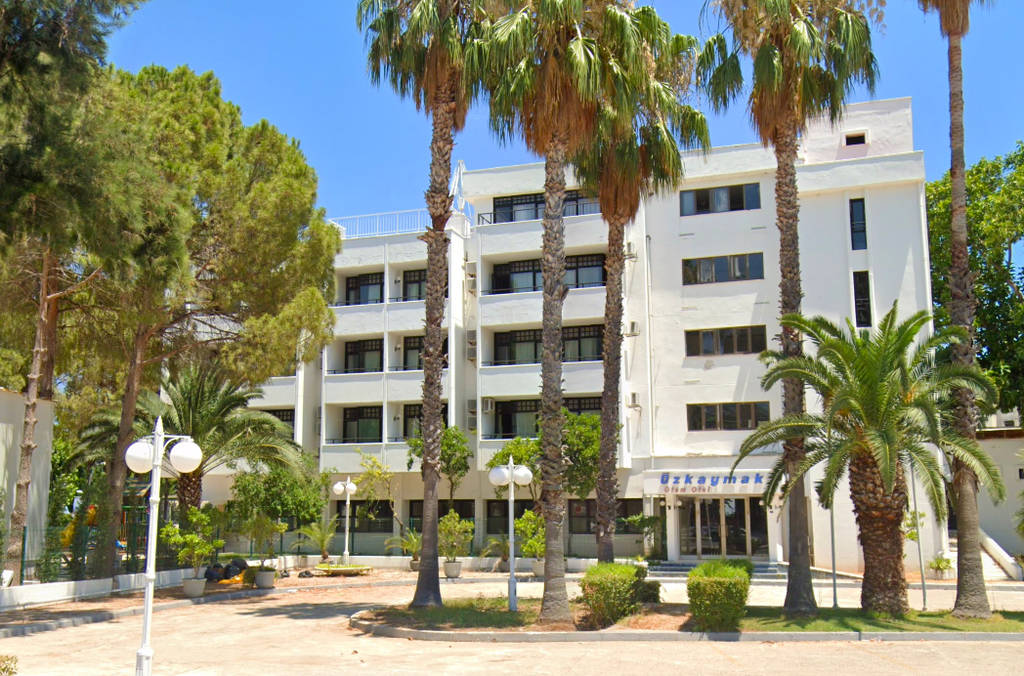 Vnější pohled na budovu hotelu obklopenou palmami. - Vnější pohled na budovu hotelu obklopenou palmami.