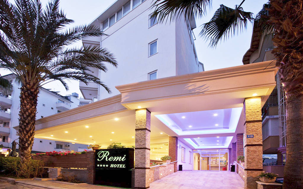 Vchod do hotelu s palmami a osvětlenou cedulí za soumraku. - Vchod do hotelu s palmami a osvětlenou cedulí za soumraku.