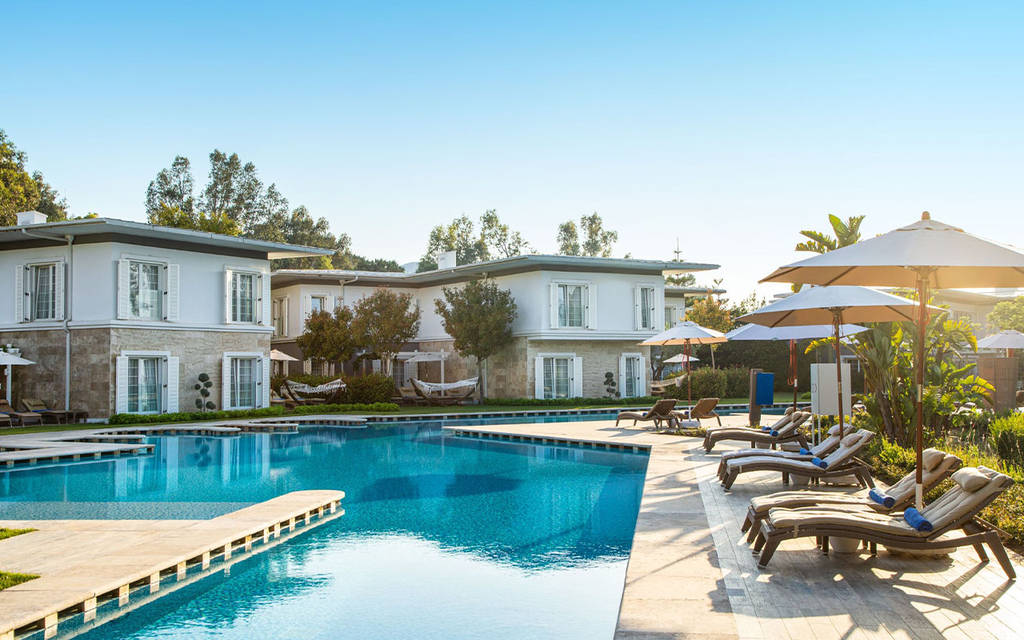 Oblast bazénu hotelu se slunečními lehátky a jasně modrou oblohou. - Oblast bazénu hotelu se slunečními lehátky a jasně modrou oblohou.