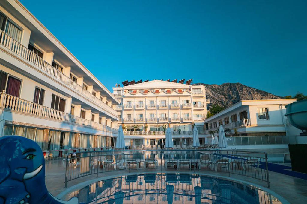 Exteriér hotelu s bazénem a vodními skluzavkami pod jasnou modrou oblohou. - Exteriér hotelu s bazénem a vodními skluzavkami pod jasnou modrou oblohou.