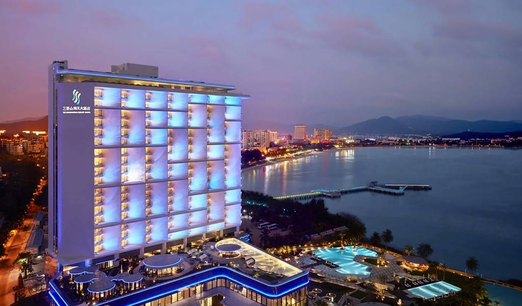 Exteriér hotelu osvětlený za soumraku s výhledem na vodu. - Exteriér hotelu osvětlený za soumraku s výhledem na vodu.