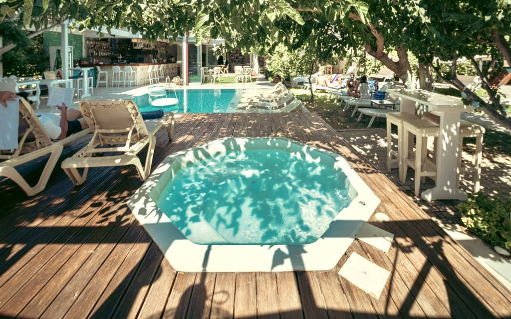 Vířivka obklopená zelení a dřevěnými lehátky u bazénu. - Vířivka obklopená zelení a dřevěnými lehátky u bazénu.