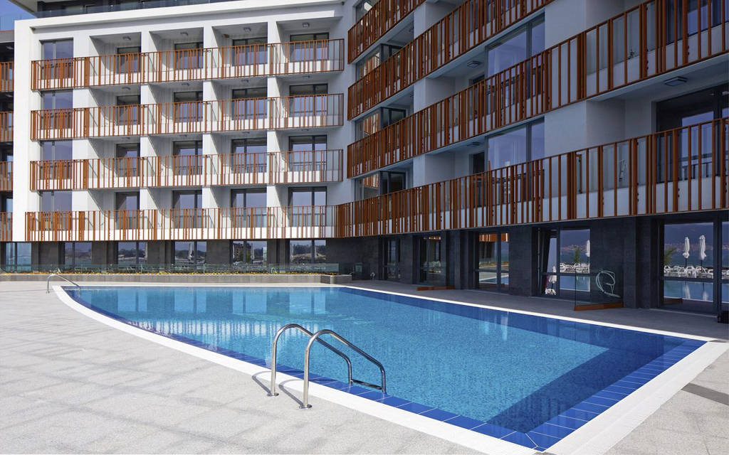 Pohled na bazénovou oblast se slunečníky a budovou hotelu v pozadí. - Pohled na bazénovou oblast se slunečníky a budovou hotelu v pozadí.