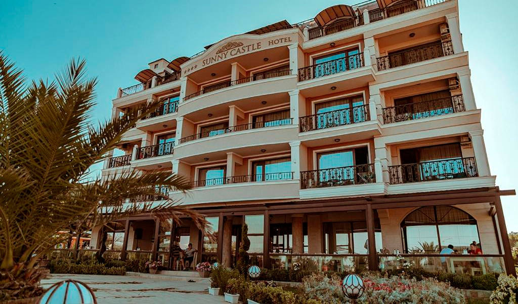 Hotel Sunny Castle s balkony a palmami v popředí. - Hotel Sunny Castle s balkony a palmami v popředí.