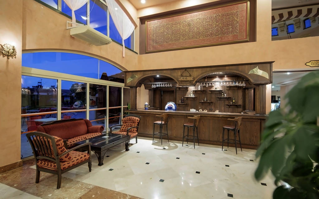 Lobby hotelu s dřevěným barem, červenými pohovkami a velkými okny za soumraku. - Lobby hotelu s dřevěným barem, červenými pohovkami a velkými okny za soumraku.