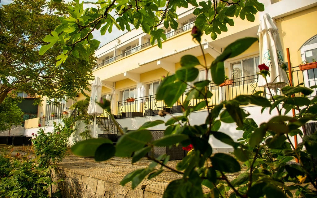 Pohled na balkony hotelu obklopené zelení a květinami. - Pohled na balkony hotelu obklopené zelení a květinami.